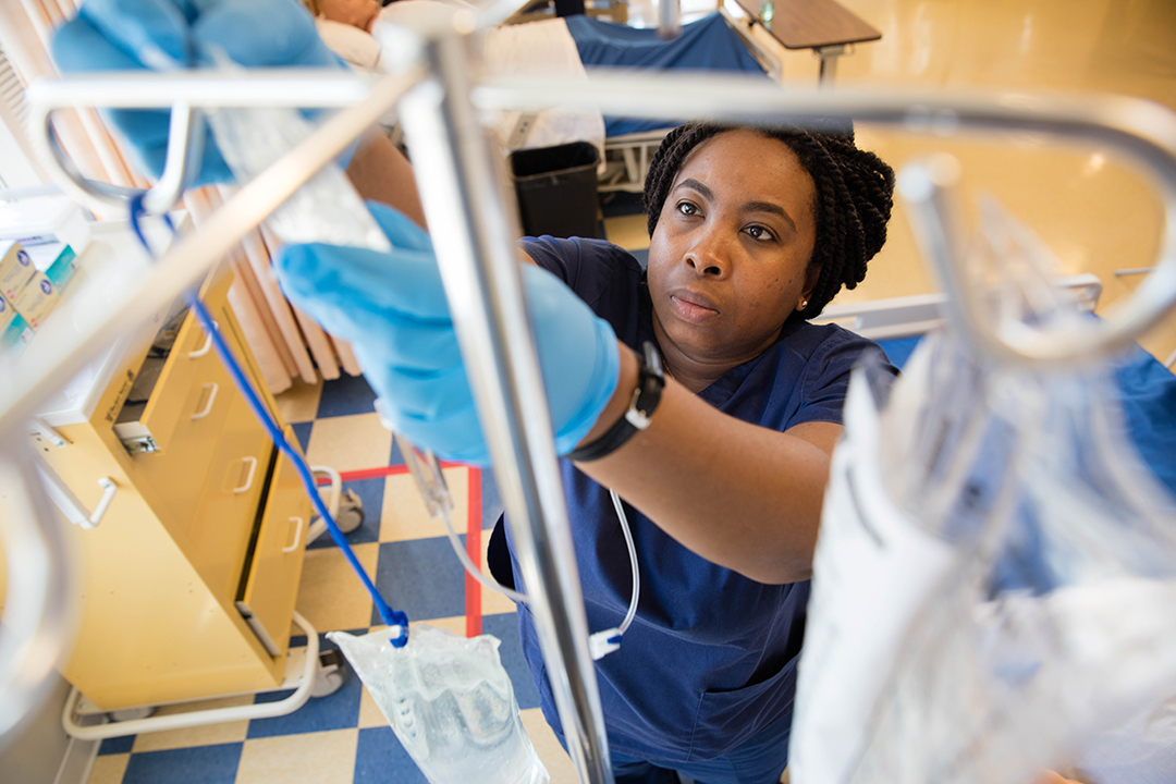 BSN student in Simulation Lab hanging IV bag